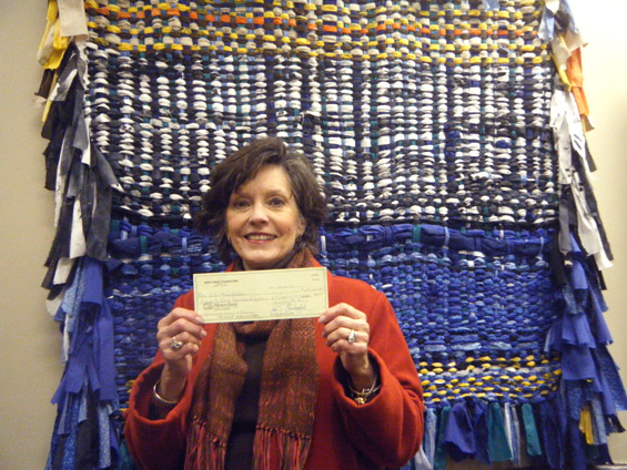 Lee Aylward, program associate for education and community outreach for the Delta Center for Culture and Learning, holds a check from the Deer Creek Foundation.